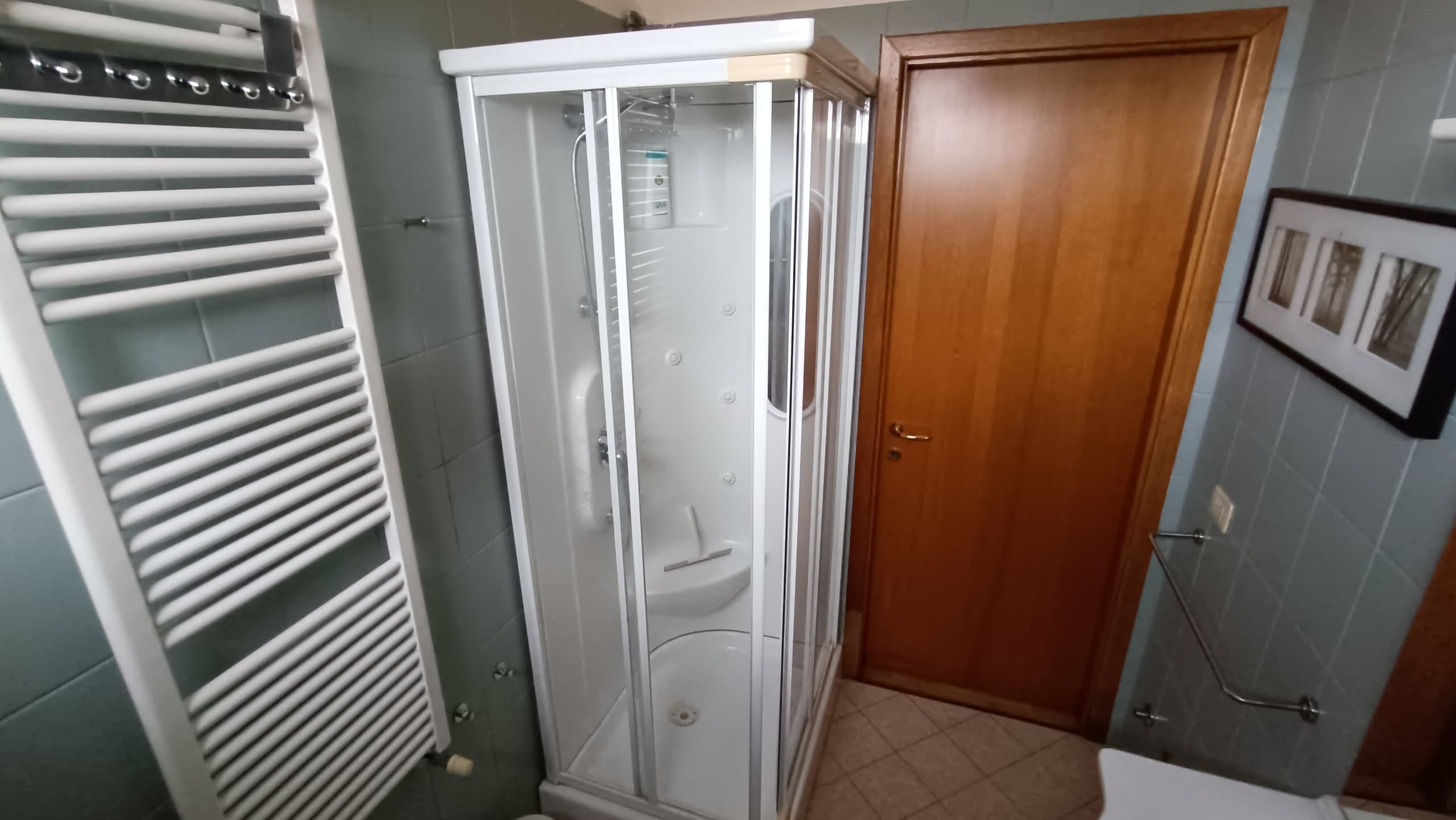 Cabina doccia idromassaggio nel bagno, con termoarredo bianco a parete