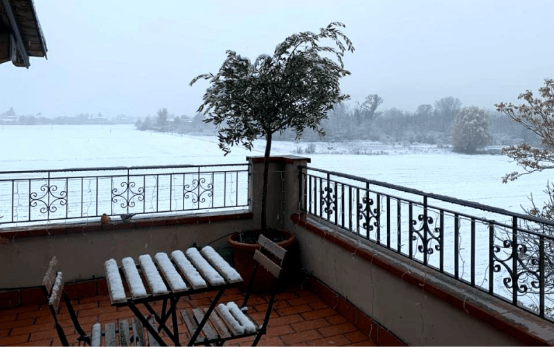 Lo stesso terrazzo dell'appartamento innevato, con vista sui campi imbiancati e sulle colline in inverno